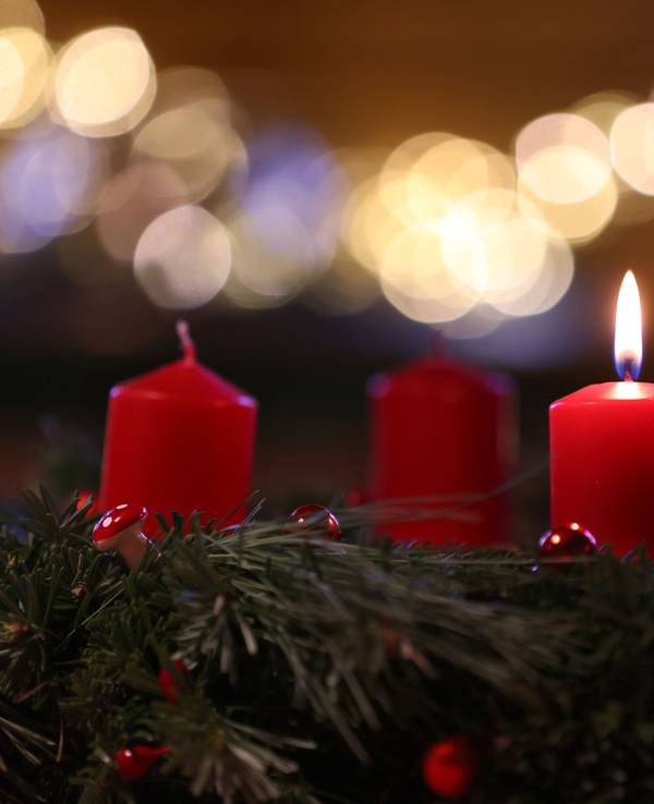 Auf dem Symbolfoto sieht man eine Kerze auf einem Adventskranz brennen.
