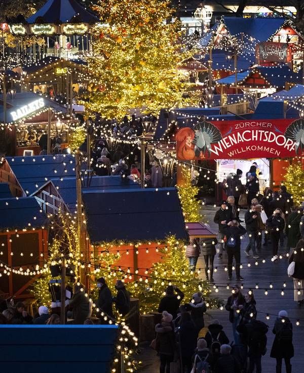 Menschen besuchen den Weihnachtsmarkt „Wienachtsdorf“ auf dem Zürcher Sechseläutenplatz.