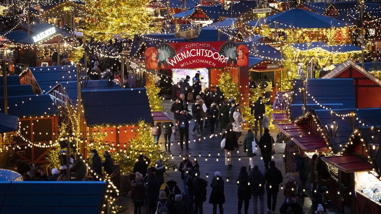 Menschen besuchen den Weihnachtsmarkt „Wienachtsdorf“ auf dem Zürcher Sechseläutenplatz.