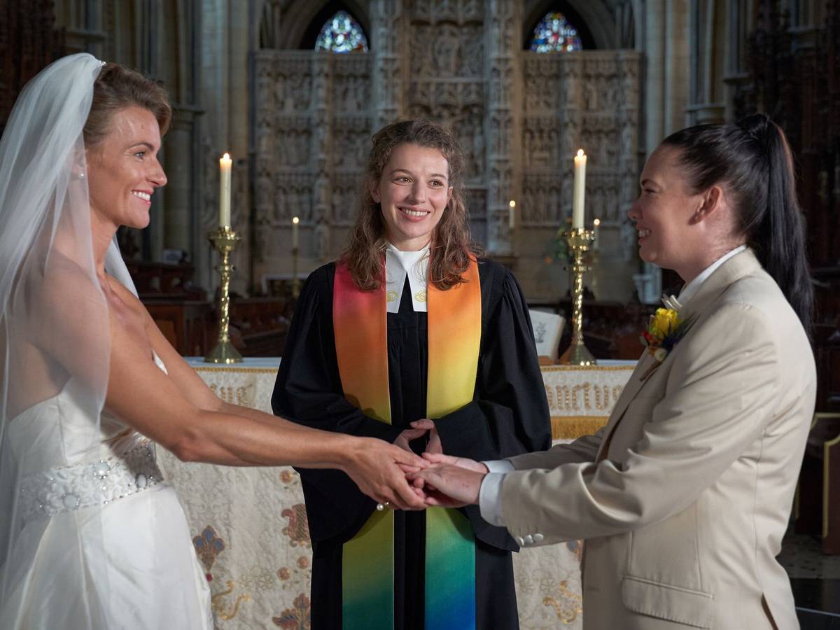 Entgegen ihren Anweisungen traut Rebecca (Antonia Bill, M.) in der Anglikanischen Gemeinde ein gleichgeschlechtliches Paar (Emma Skinner, l., und Rachel Leigh, r.).