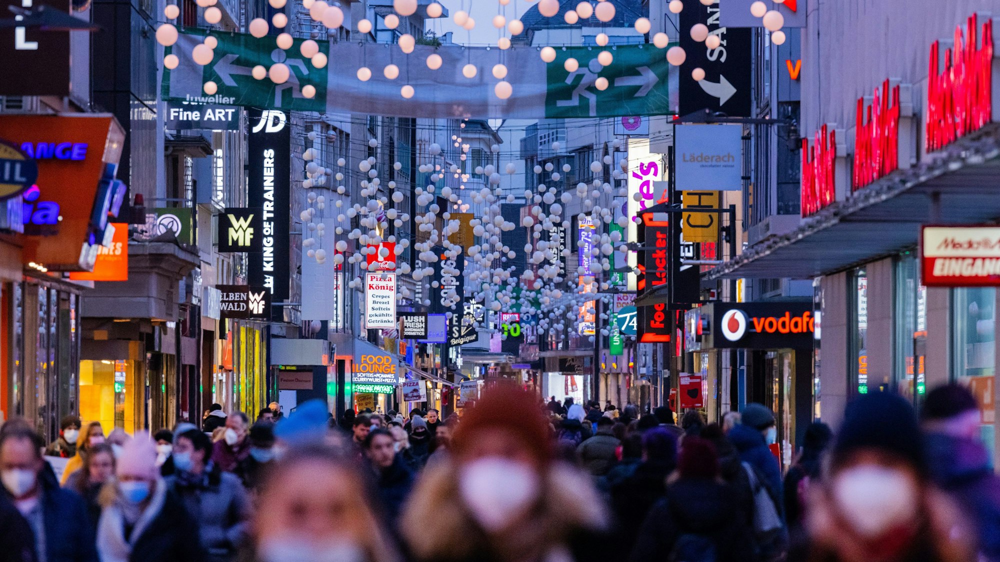 Menschen gehen in der Dämmerung über die Einkaufsstraße Hohe Straße.