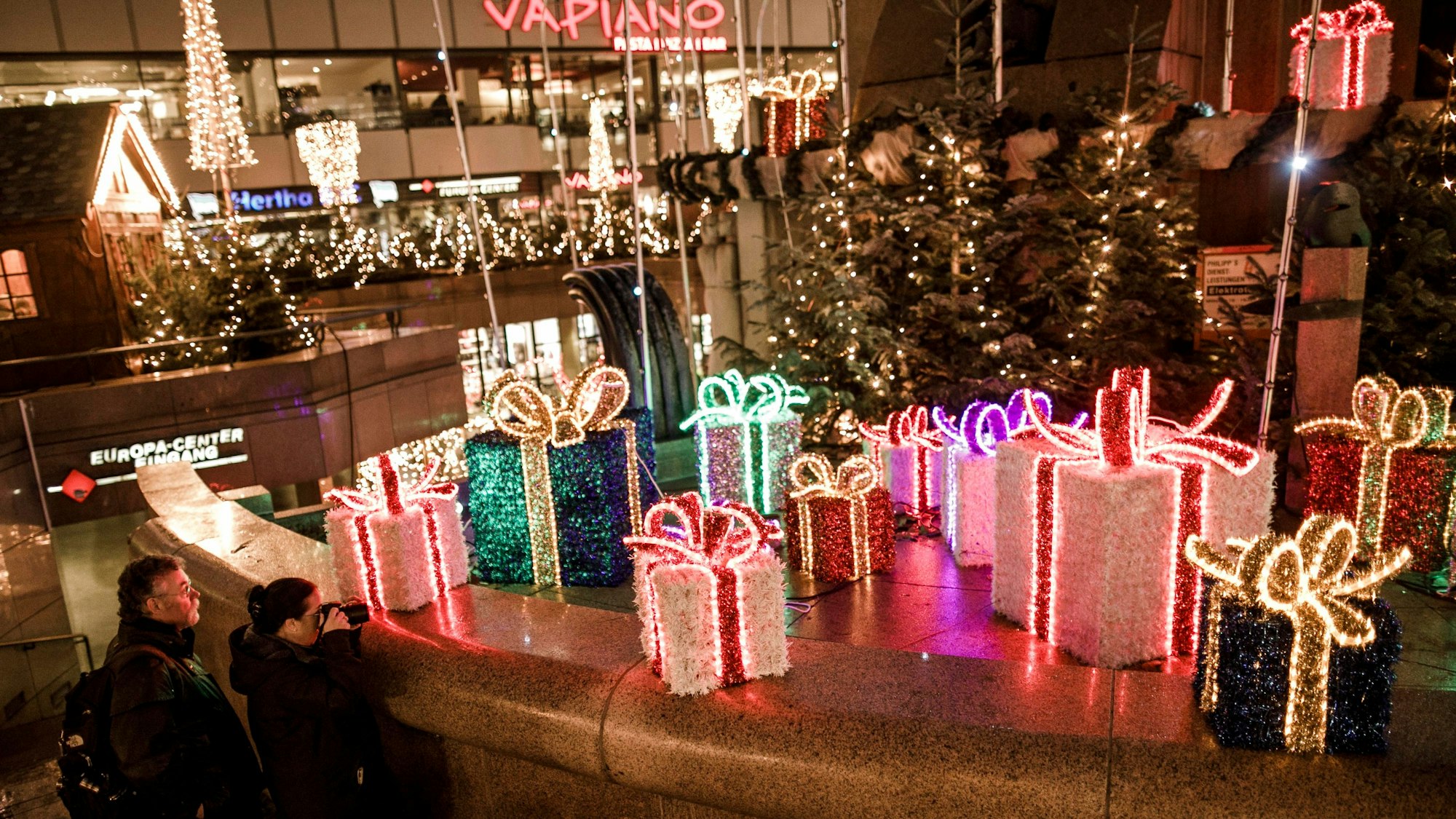 Besucher gehen an Weihnachtsdekorationen auf dem Weihnachtsmarkt am Breitscheidplatz vorbei.