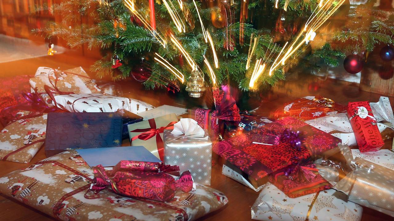 Verpackte Weihnachtsgeschenke liegen unter einem Christbaum.
