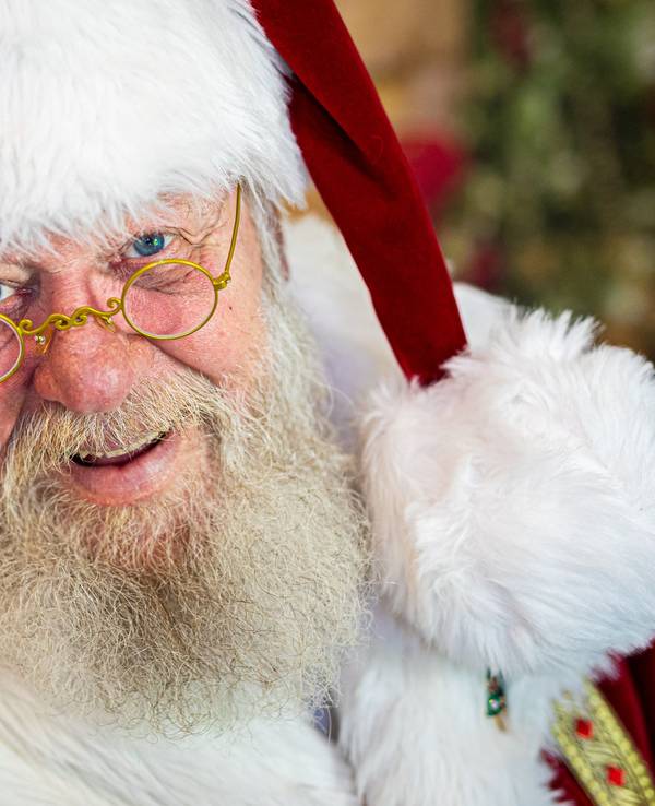 Weihnachtsmann Willi Dahmen sitzt in seinem Büro und lächelt in die Kamera.