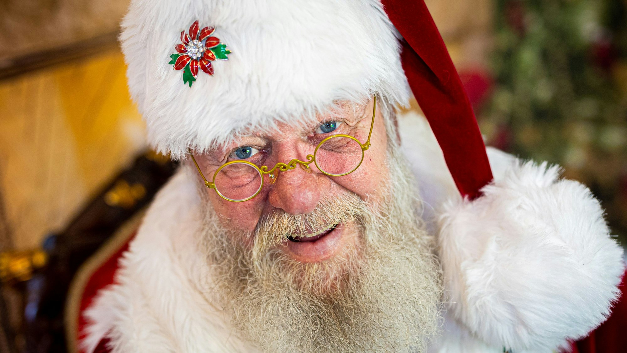 Weihnachtsmann Willi Dahmen sitzt in seinem Büro und lächelt in die Kamera.