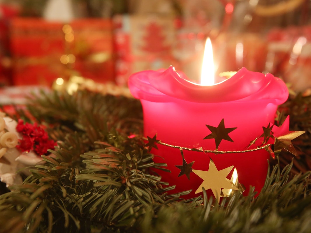 Eine Adventskerze brennt am 24.12.2013 in Hamburg, im Hintergrund liegen Weihnachtsgeschenke.