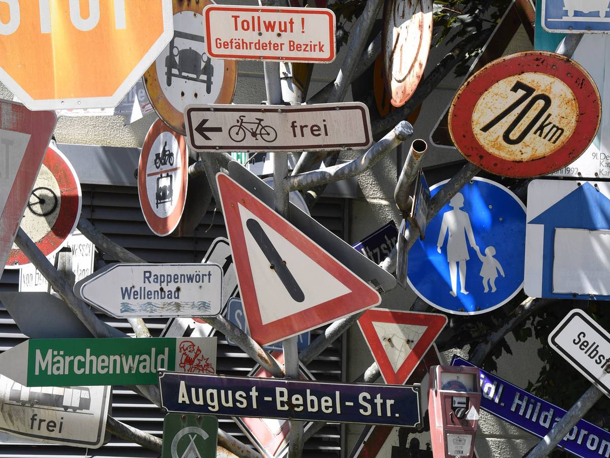 Ein Schilderbaum steht beim Tiefbauamt in Bayern. Dieser besteht aus ausrangierten Verkehrs- und Hinweisschildern.
