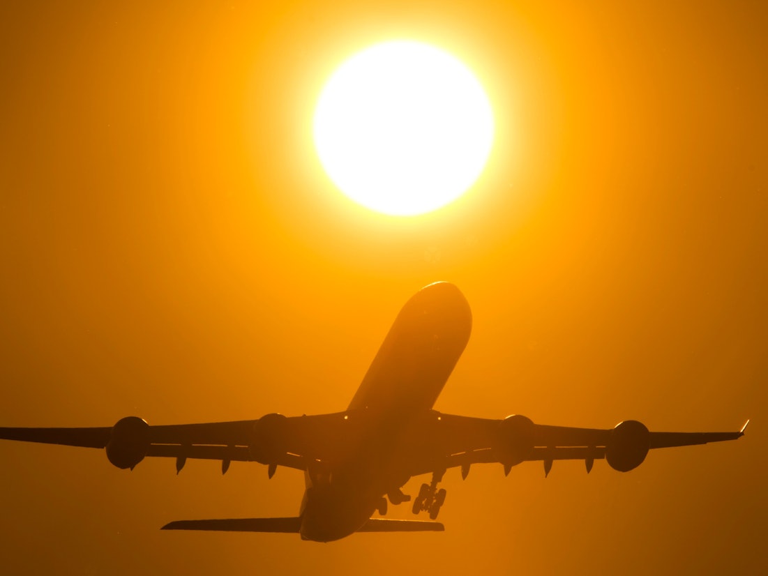 Ein Flugzeug startet in den Sonnenuntergang.