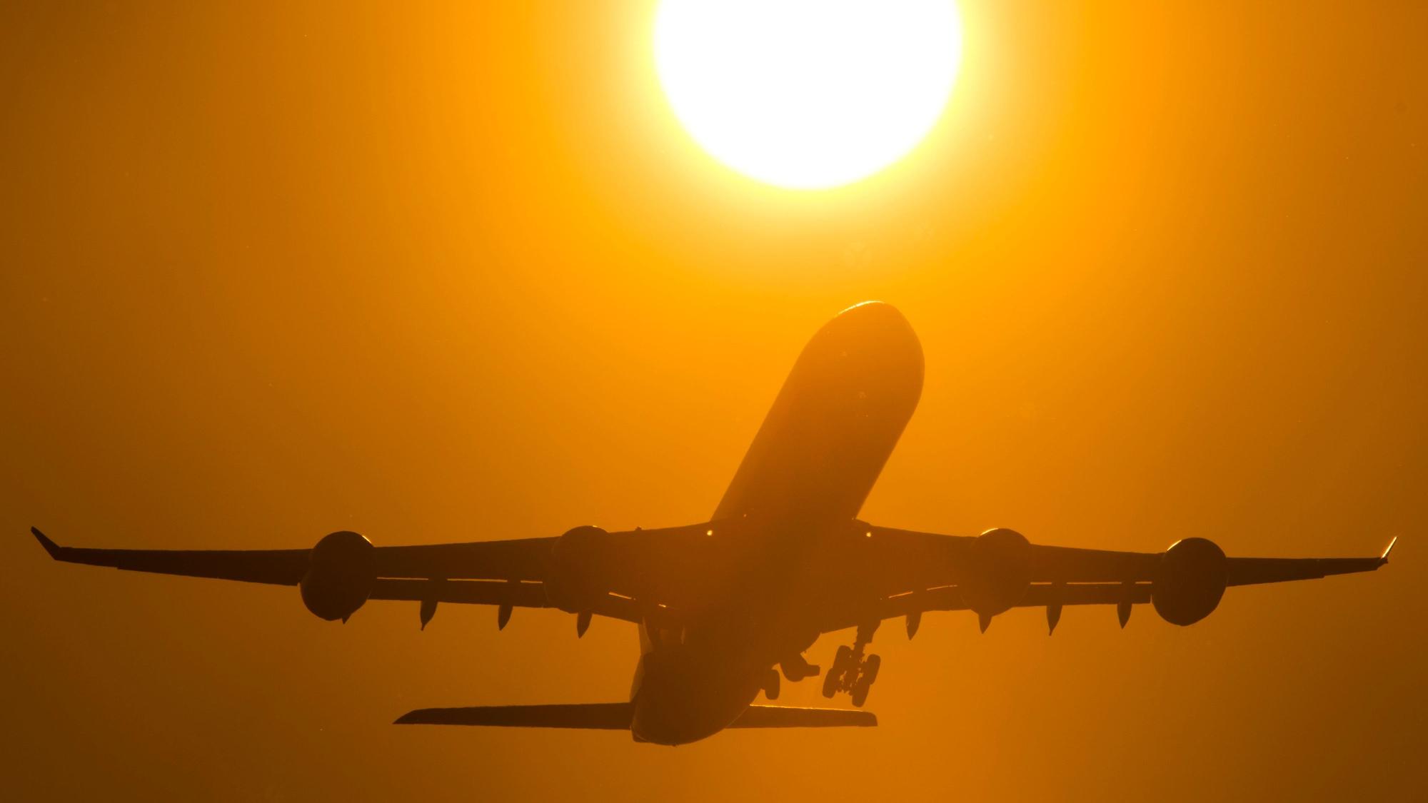 Ein Flugzeug startet in den Sonnenuntergang.