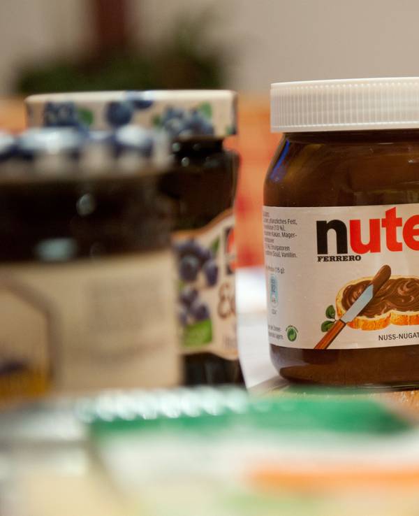 Ein Glas Nutella steht auf einem Frühstückstisch.