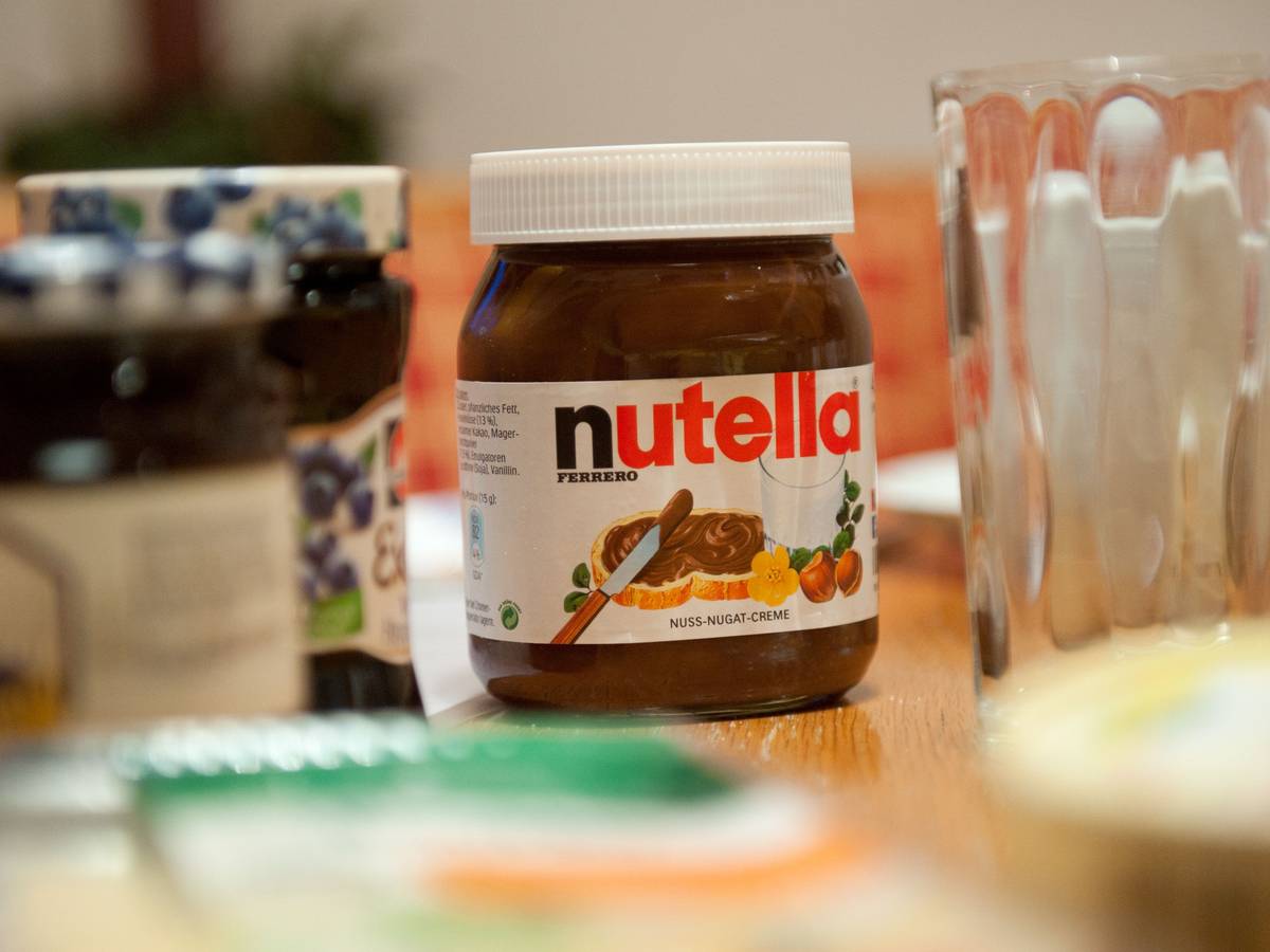 Ein Glas Nutella steht auf einem Frühstückstisch.