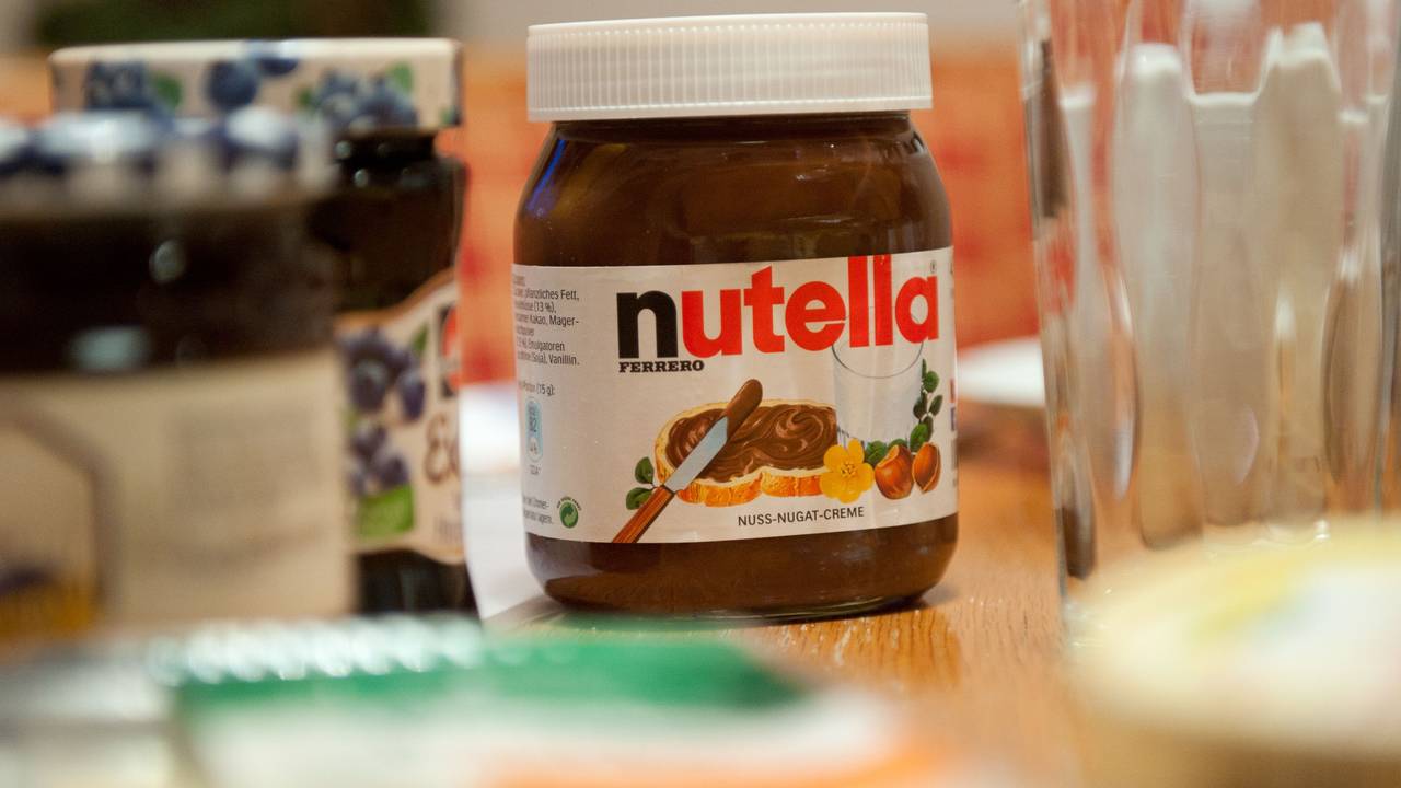Ein Glas Nutella steht auf einem Frühstückstisch.