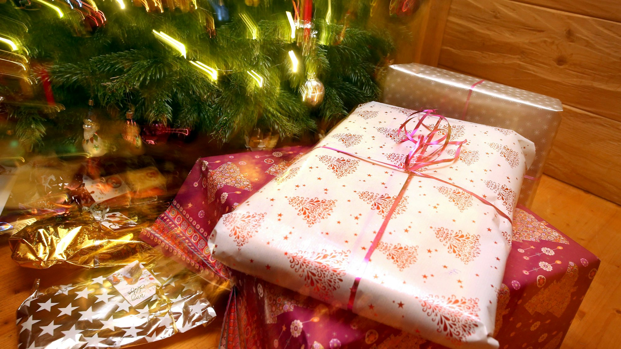 Weihnachtsgeschenke liegen unter einem geschmücktem Christbaum.