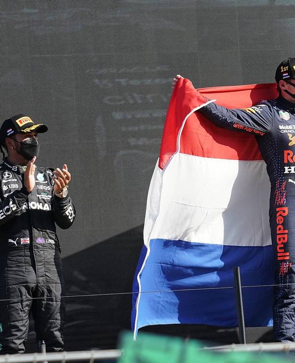 Der Zweitplatzierte Lewis Hamilton (l) aus Großbritannien vom Team Mercedes-AMG Petronas Formula One Team applaudiert während der Sieger Max Verstappen aus den Niederlanden vom Team Red Bull Racing Honda eine niederländische Fahne hält.