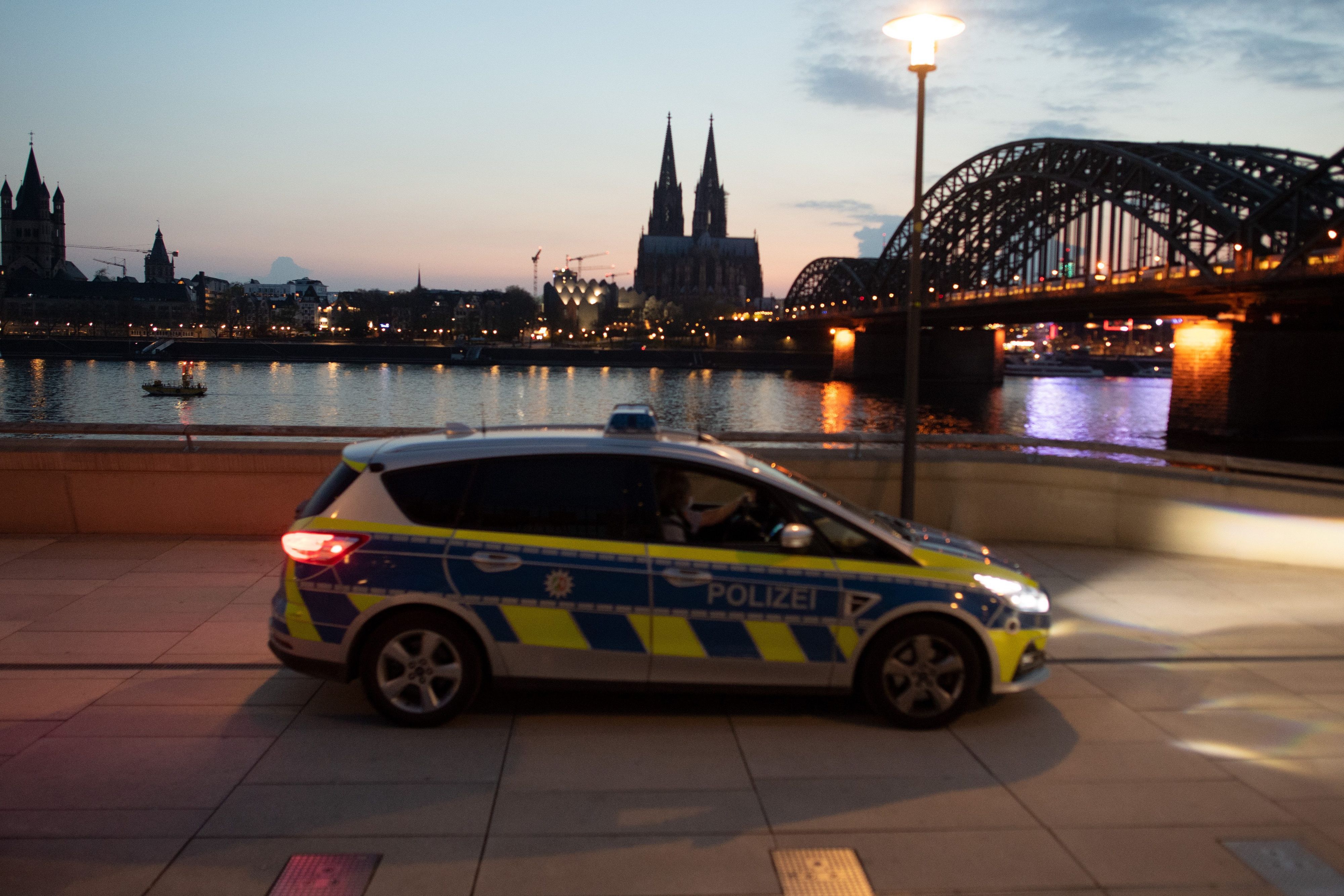 Ein Polizeiauto fährt am Rheinufer Streife mit dem Dom im Hintergrund.