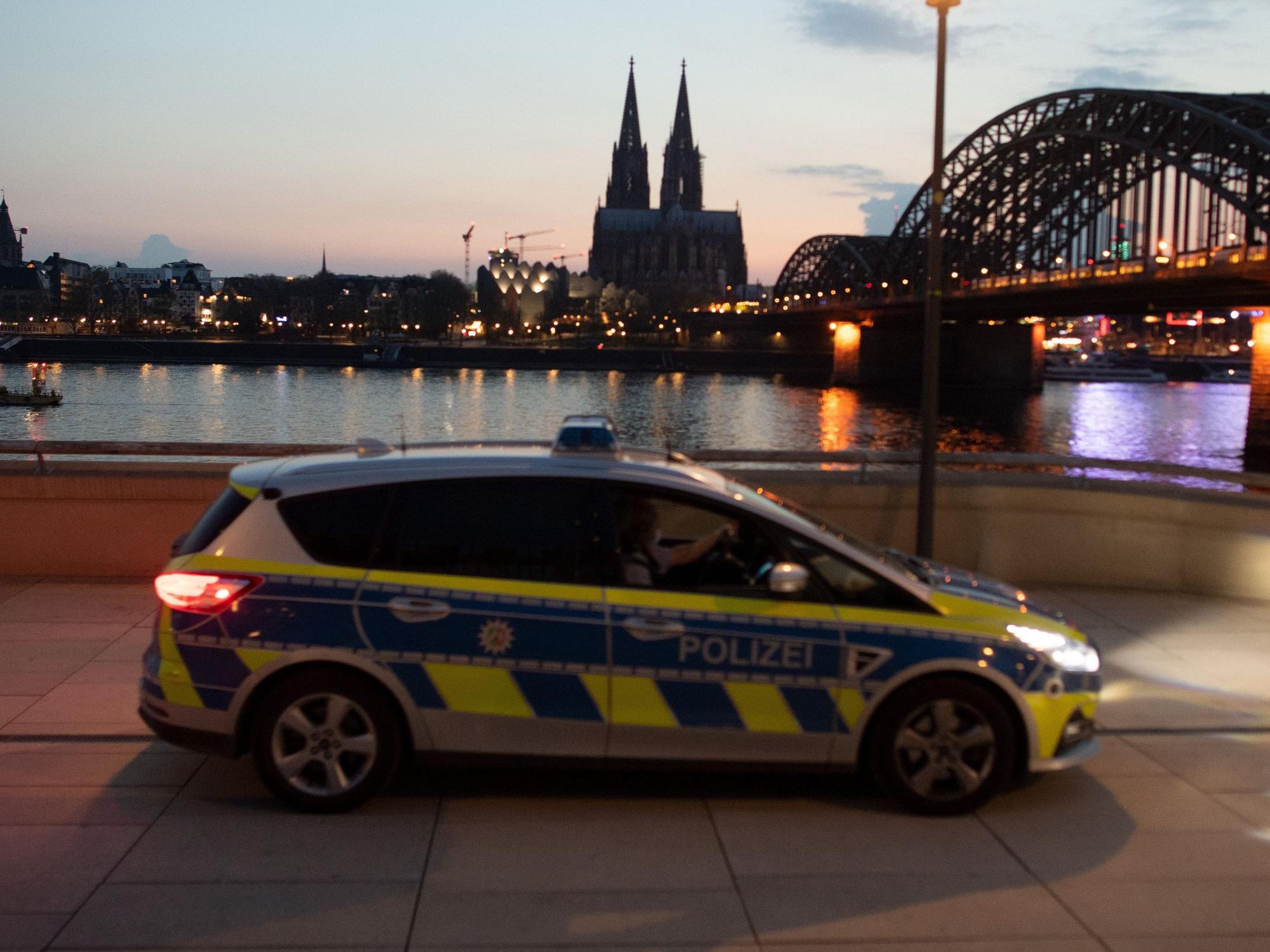 Ein Polizeiauto fährt am Rheinufer Streife mit dem Dom im Hintergrund.