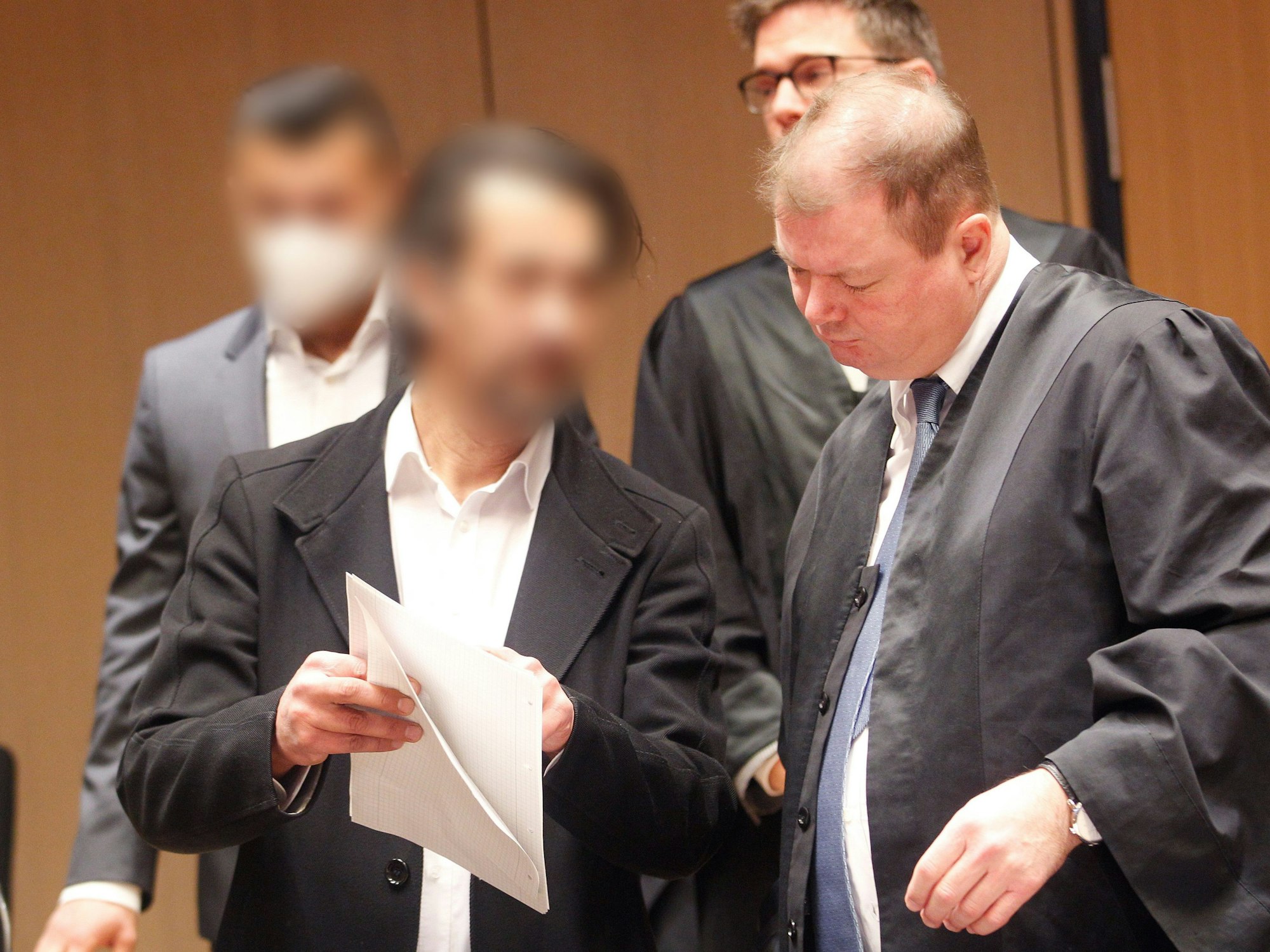 Zwei Männer stehen in Bochum vor Gericht, einer zeigt seinem Verteidiger ein Schriftstück.