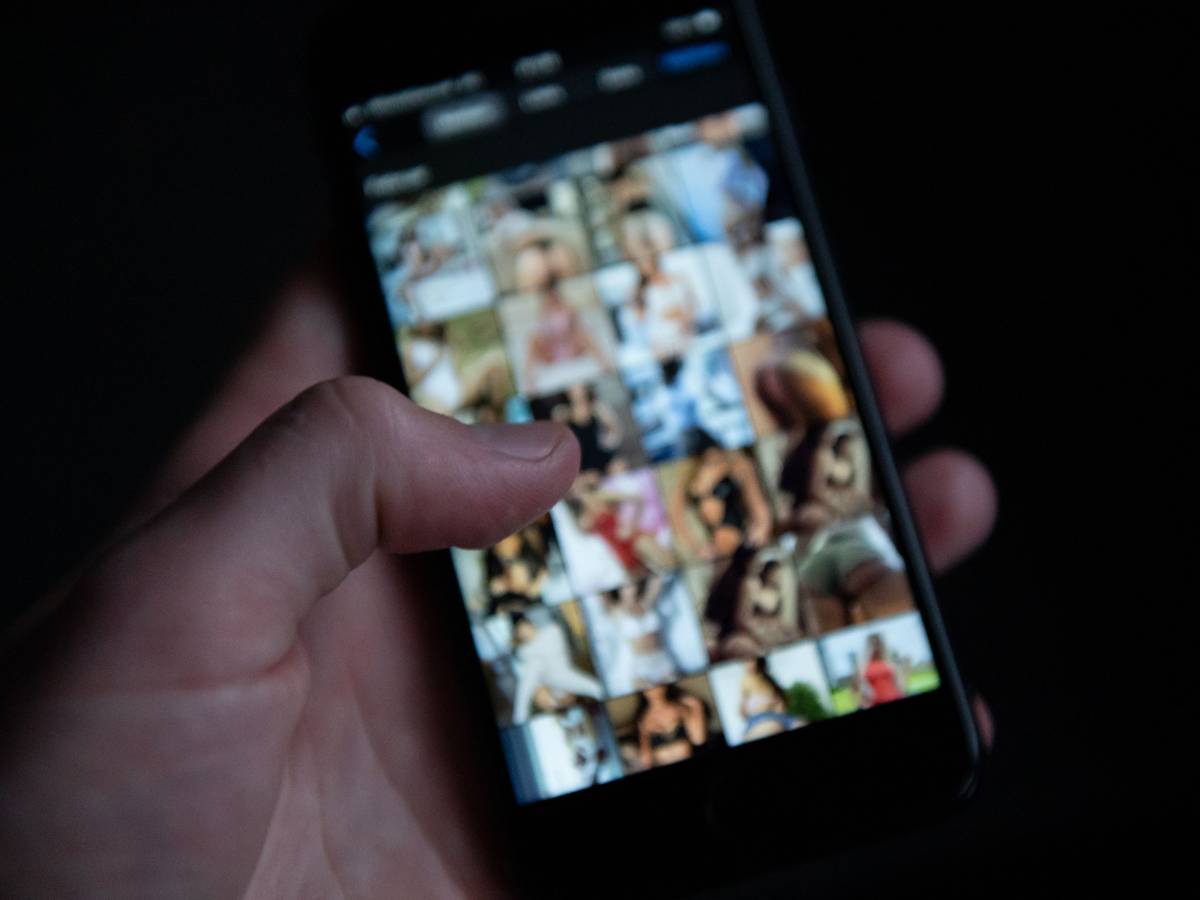 Ein Mann schaut sich auf einem Smartphone pornografische Bilder an.