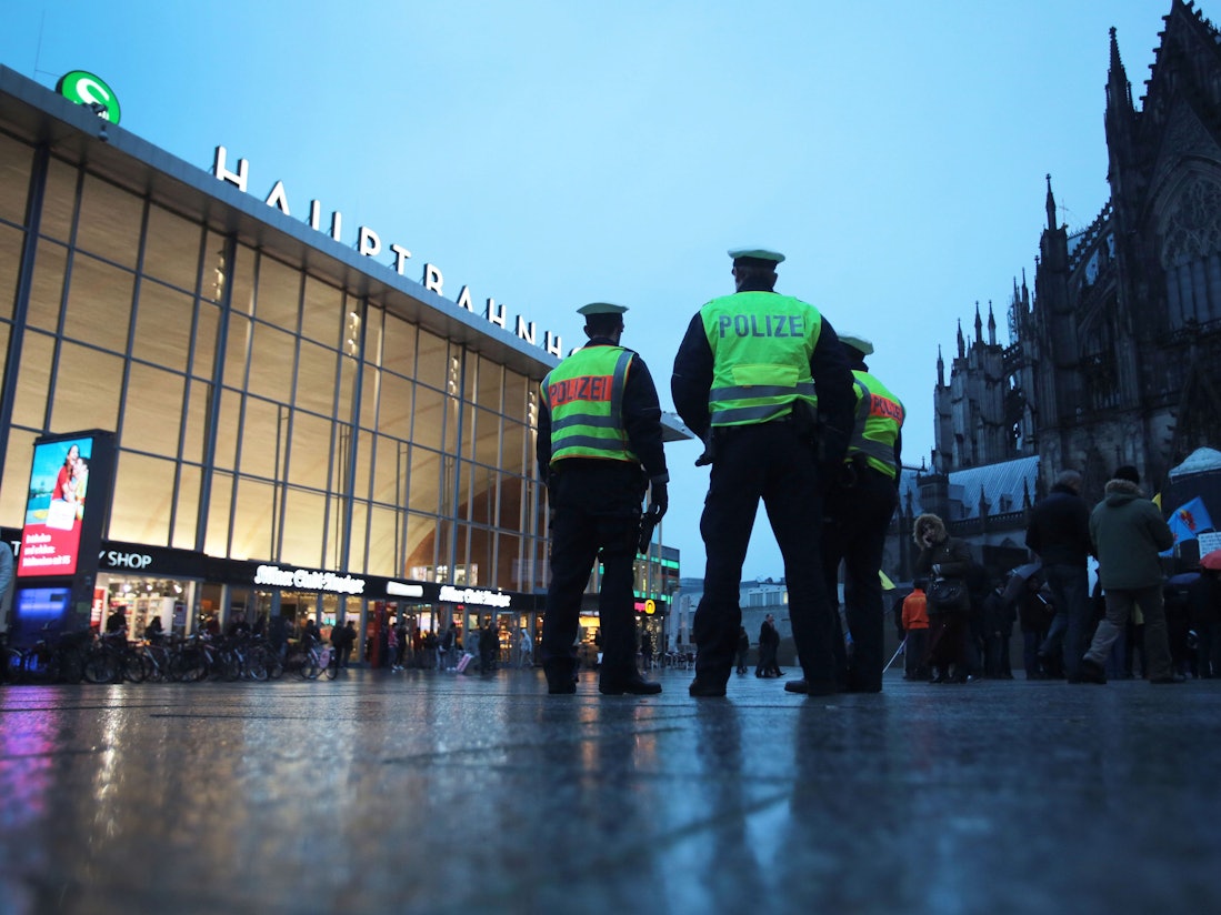 Drei Polizisten stehen in Köln vor dem Hauptbahnhof.