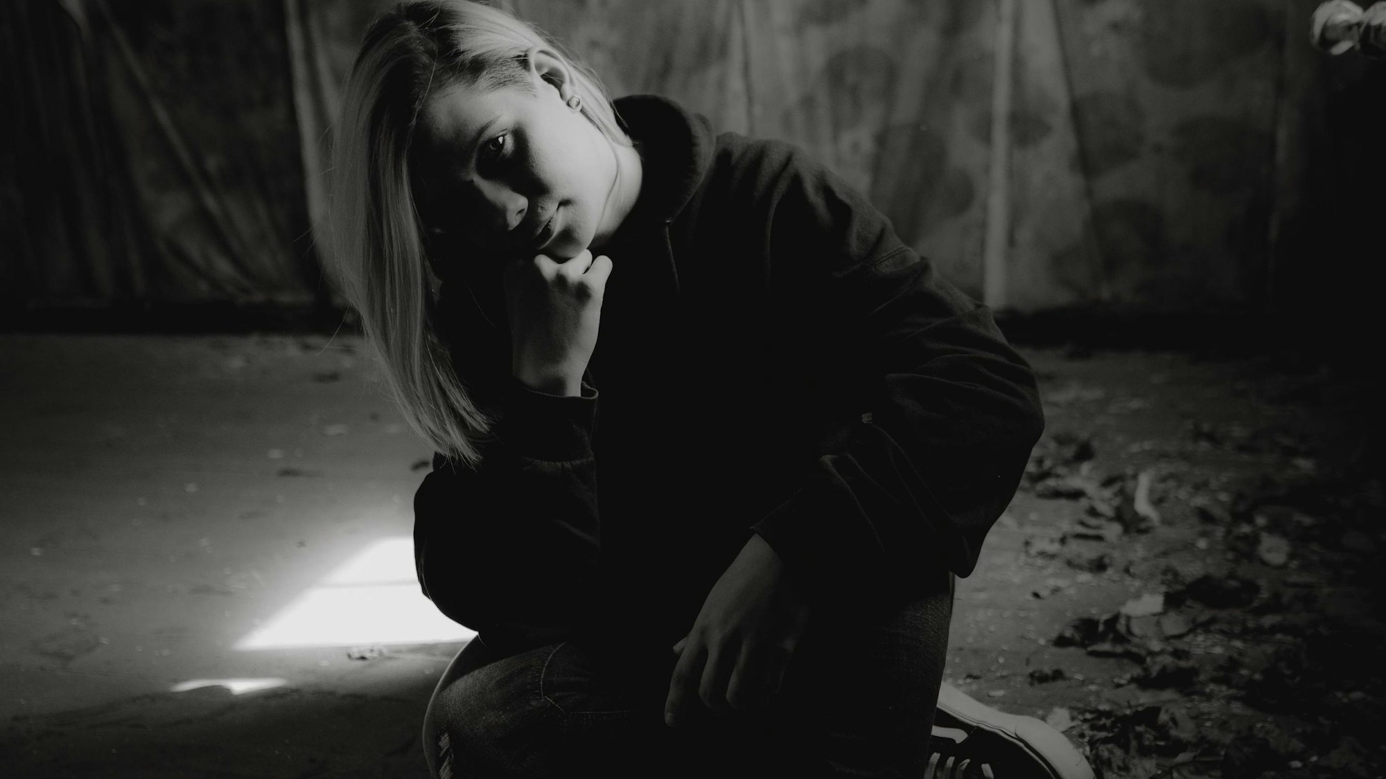 Katha Rosa
sitzt auf dem Boden und hat das Kinn auf die rechte Hand gestützt. Das Foto ist schwarz weiß.