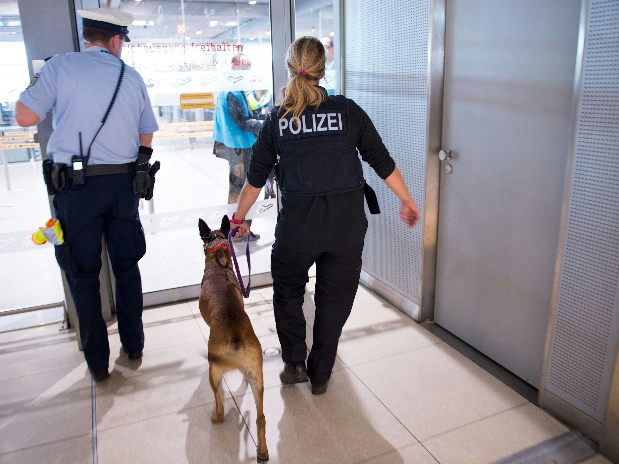 Polizisten mit einem Hund betreten 30.05.2016 den Sicherheitsbereich im Terminal 1 am Flughafen Köln/Bonn (Nordrhein-Westfalen).