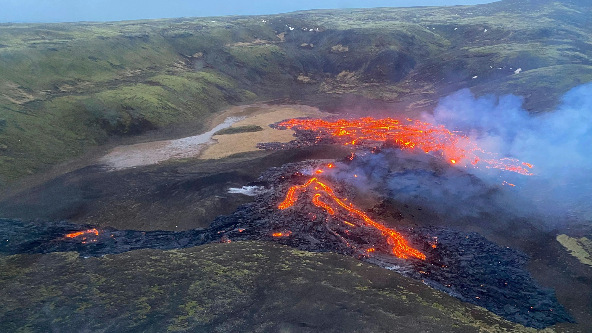 Eine Luftaufnahme der Küstenwache zeigt, wie Lava aus dem Vulkan Fagradalsfjall fließt und Rauch aufsteigt.