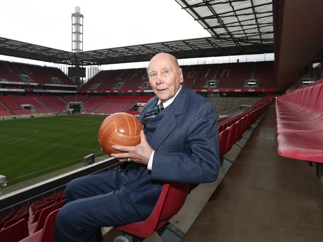 Horst Eckel sitzt mit einem alten Fußball im Stadion.