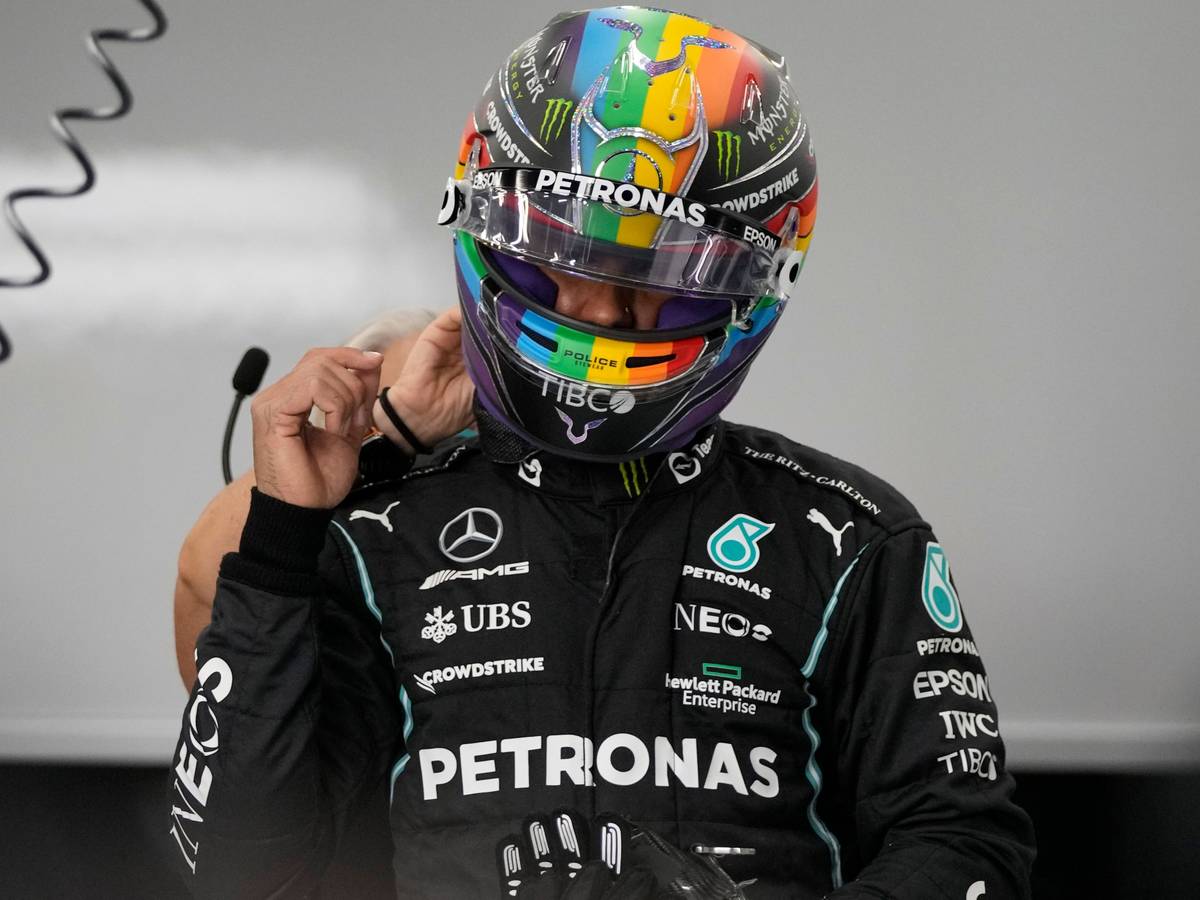 Lewis Hamilton steht in Rennmontur in der Box.