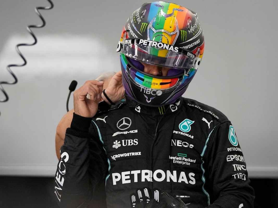 Lewis Hamilton steht in Rennmontur in der Box.
