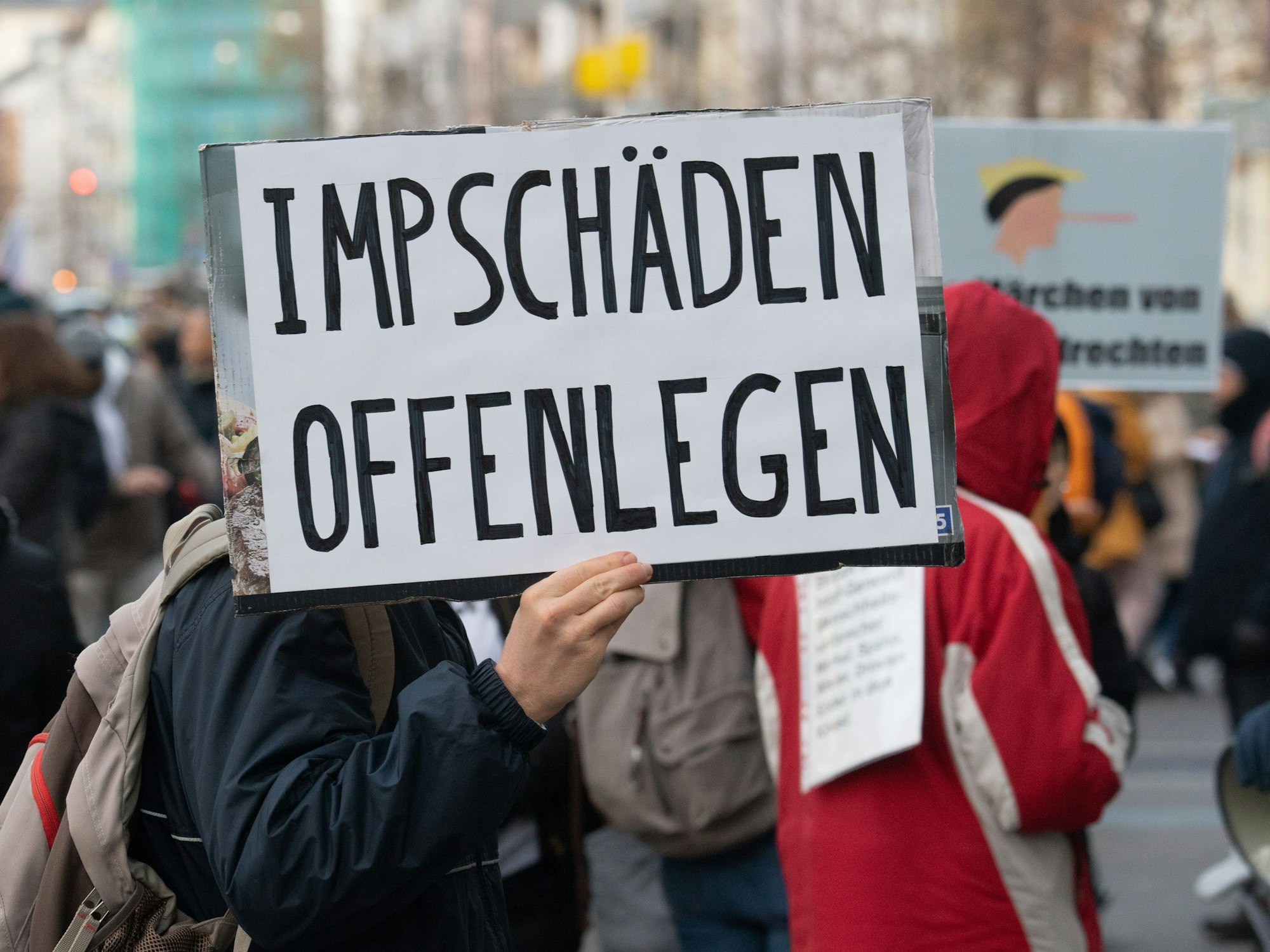 Teilnehmer einer Demonstration hält ein Schild mit der Auschrift "Impschäden offenlegen". Mehr als zweitausend Impfgegner, Coronaleugner und Querdenker demonstrieren in der Innenstadt von Frankfurt am Main.