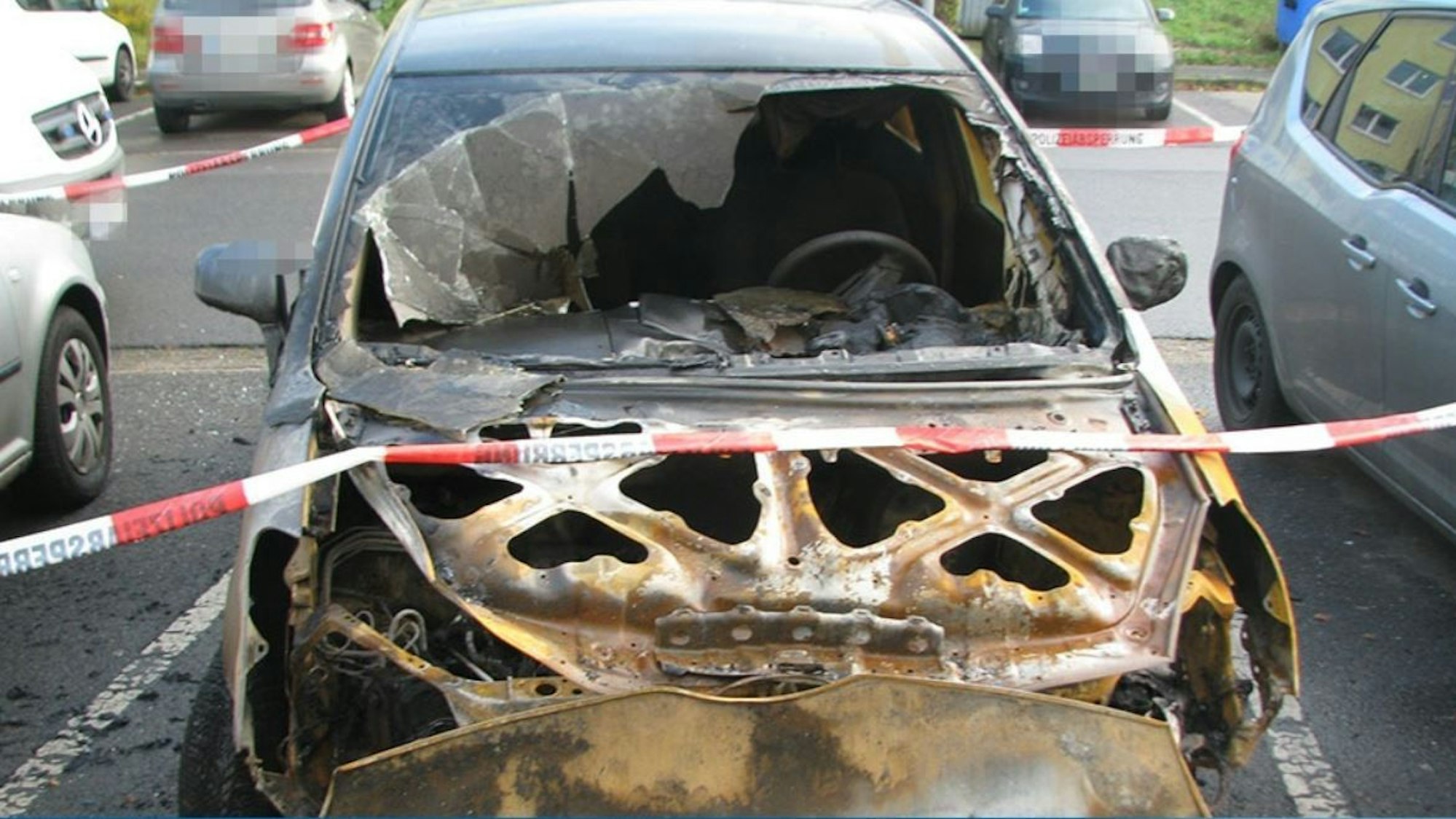 Ausgebrannter Toyota auf einem Parkplatz.
