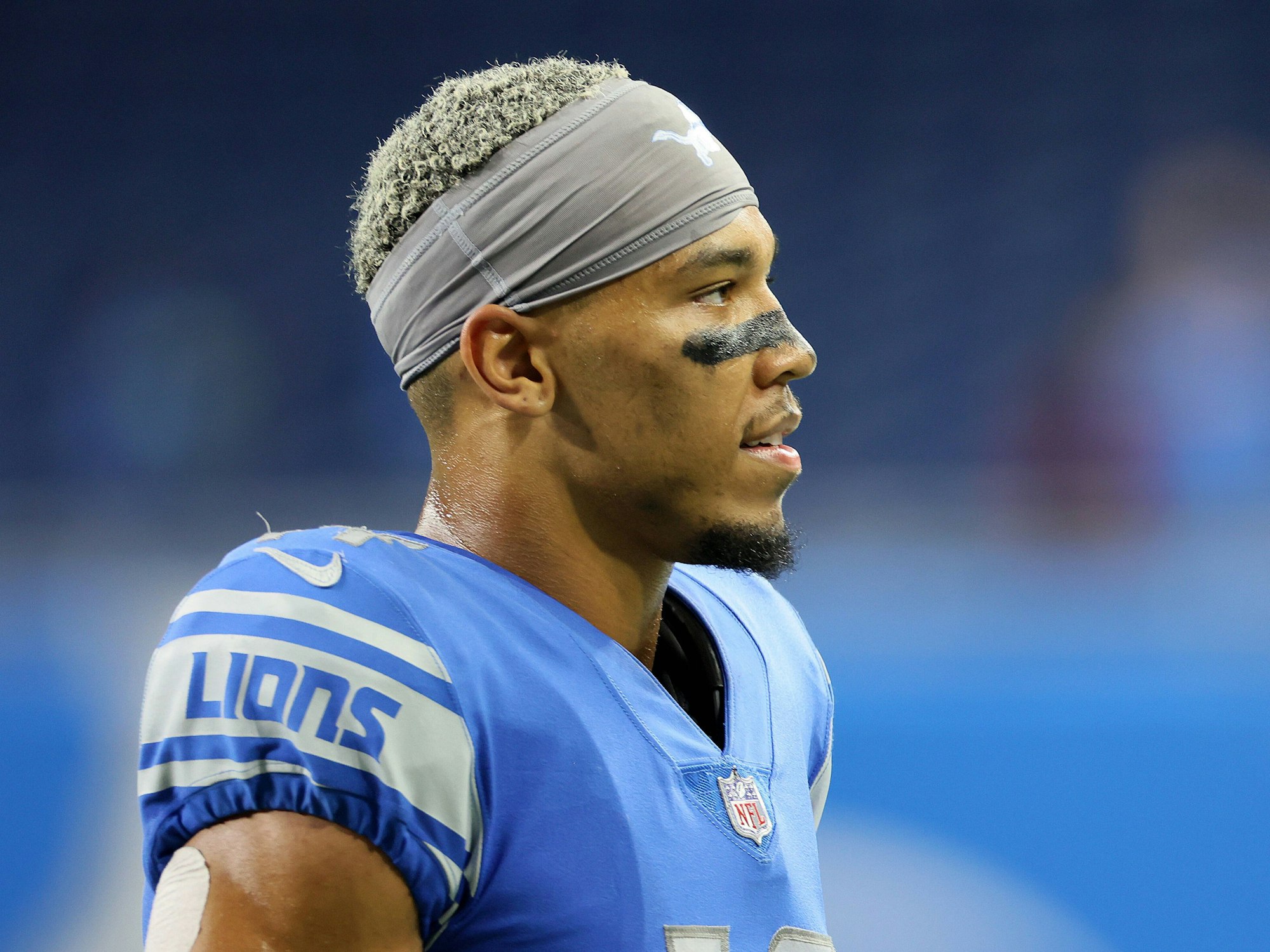 Amon-Ra St. Brown ist im Profil zu sehen. Er trägt ein Stirnband und hat einen schwarzen Strich unter den Augen, der über die Nase verläuft.