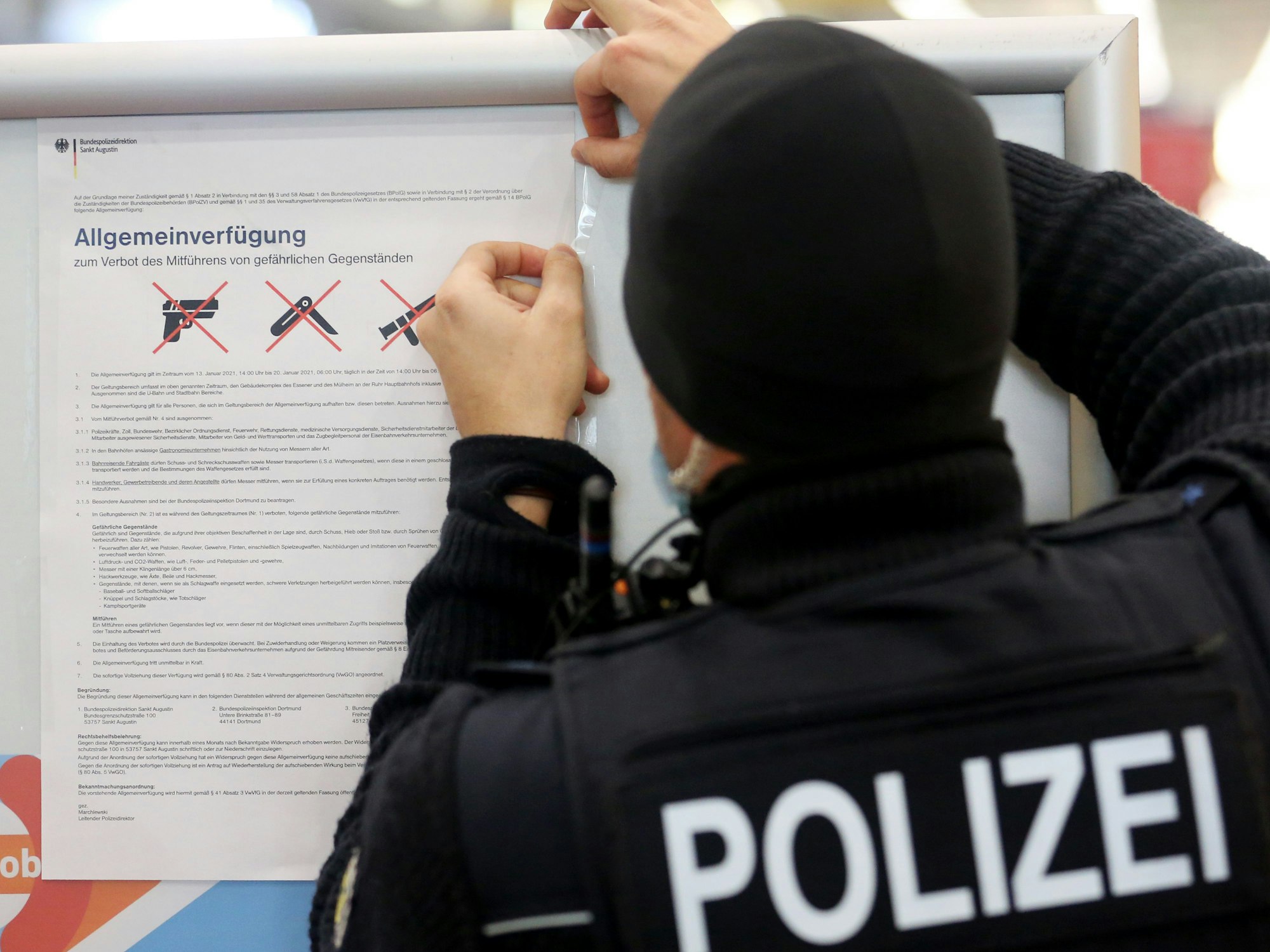 Ein Bundespolizist hängt ein Plakat auf