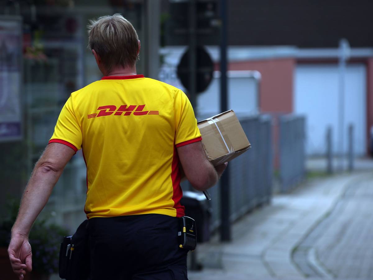 Ein Paketzustellerder von Deutsche Post DHL liefert ein Paket aus.