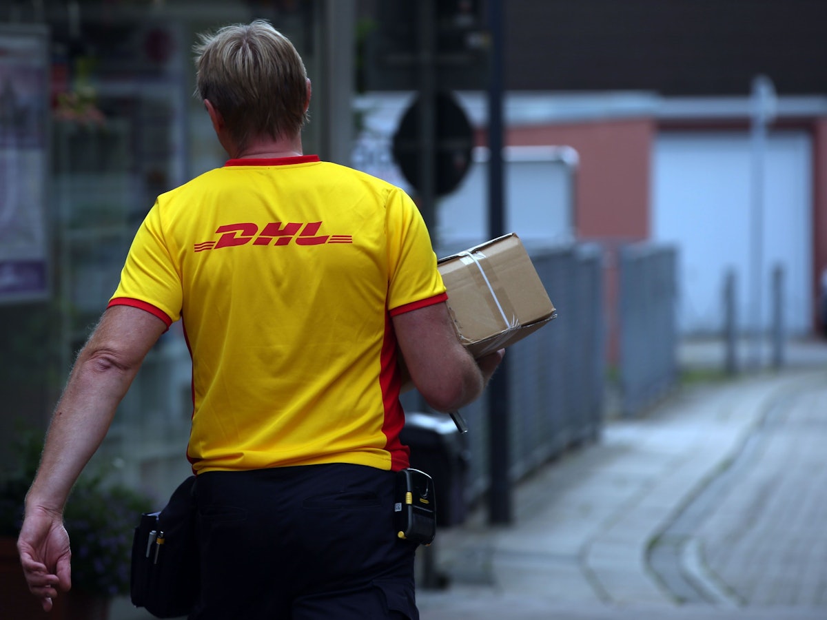 Ein Paketzustellerder von Deutsche Post DHL liefert ein Paket aus.
