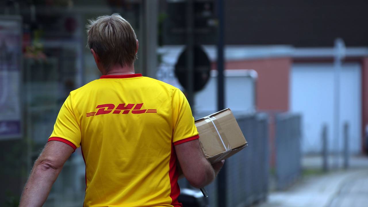 Ein Paketzustellerder von Deutsche Post DHL liefert ein Paket aus.