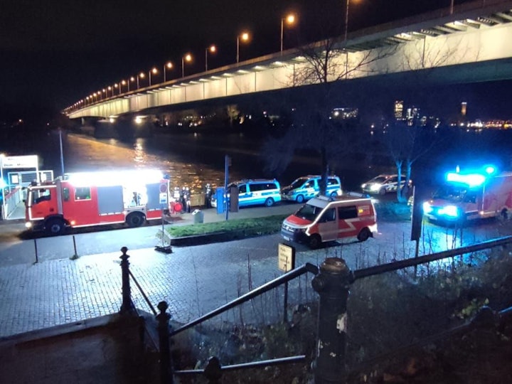 Polizei und Feuerwehr stehen am Rheinufer unter der Zoobrücke. Dort war ein Taxi in den Rhein gefahren.