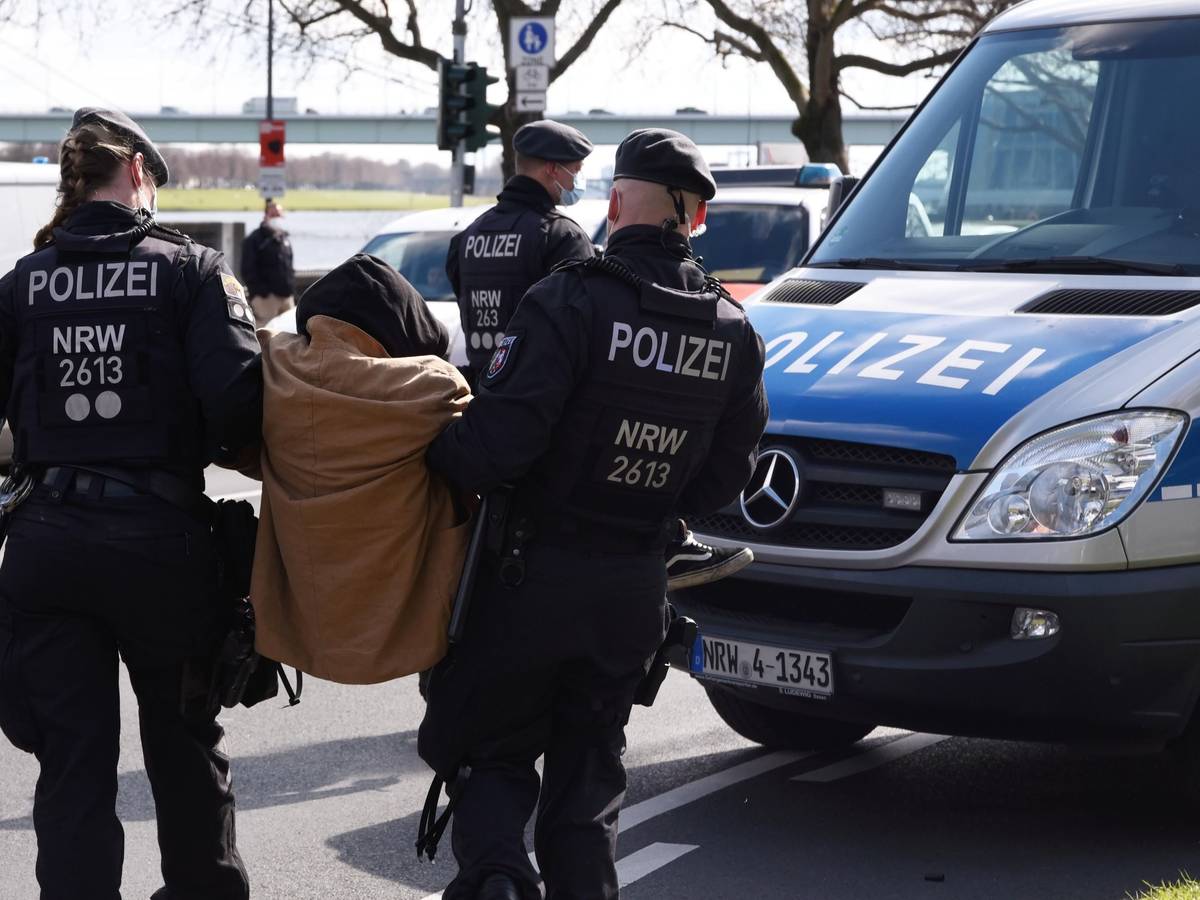 Zwei Beamte der Polizei tragen einen Demonstranten zu einem Einsatzwagen.