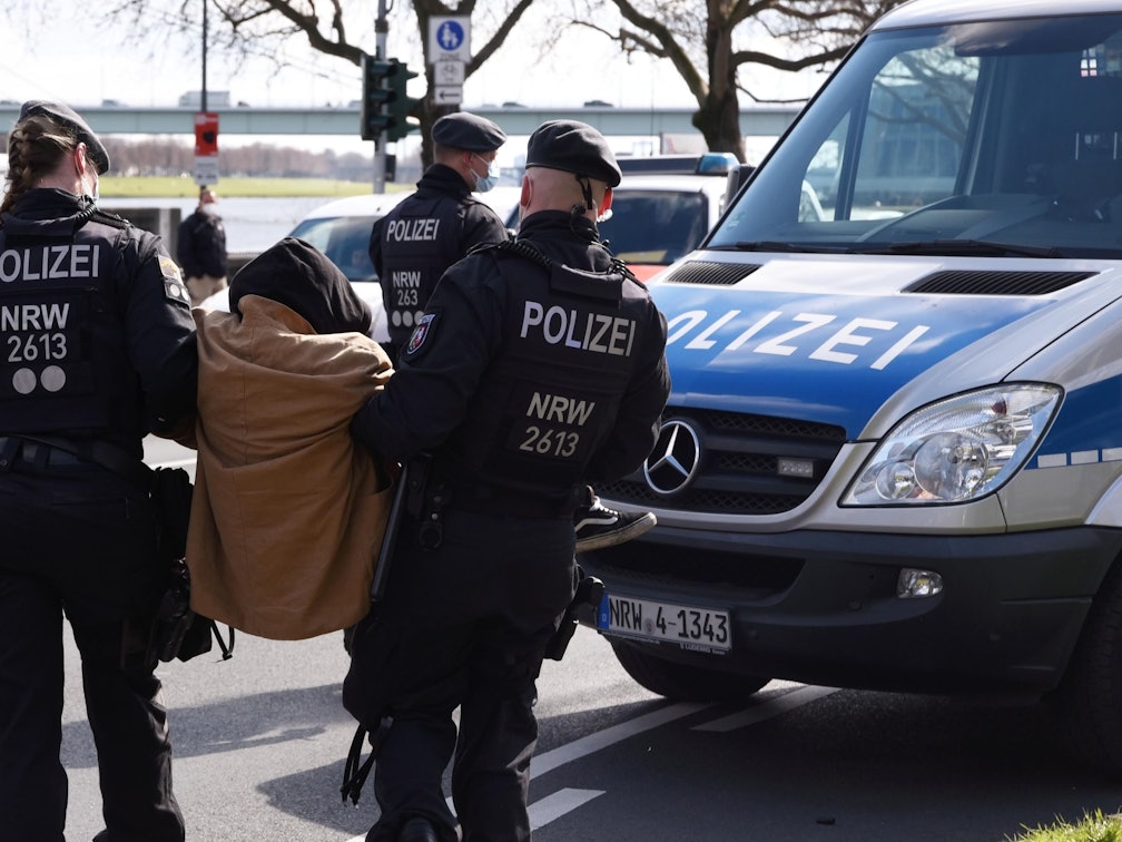 Zwei Beamte der Polizei tragen einen Demonstranten zu einem Einsatzwagen.