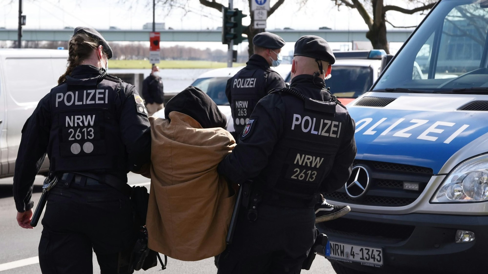 Zwei Beamte der Polizei tragen einen Demonstranten zu einem Einsatzwagen.