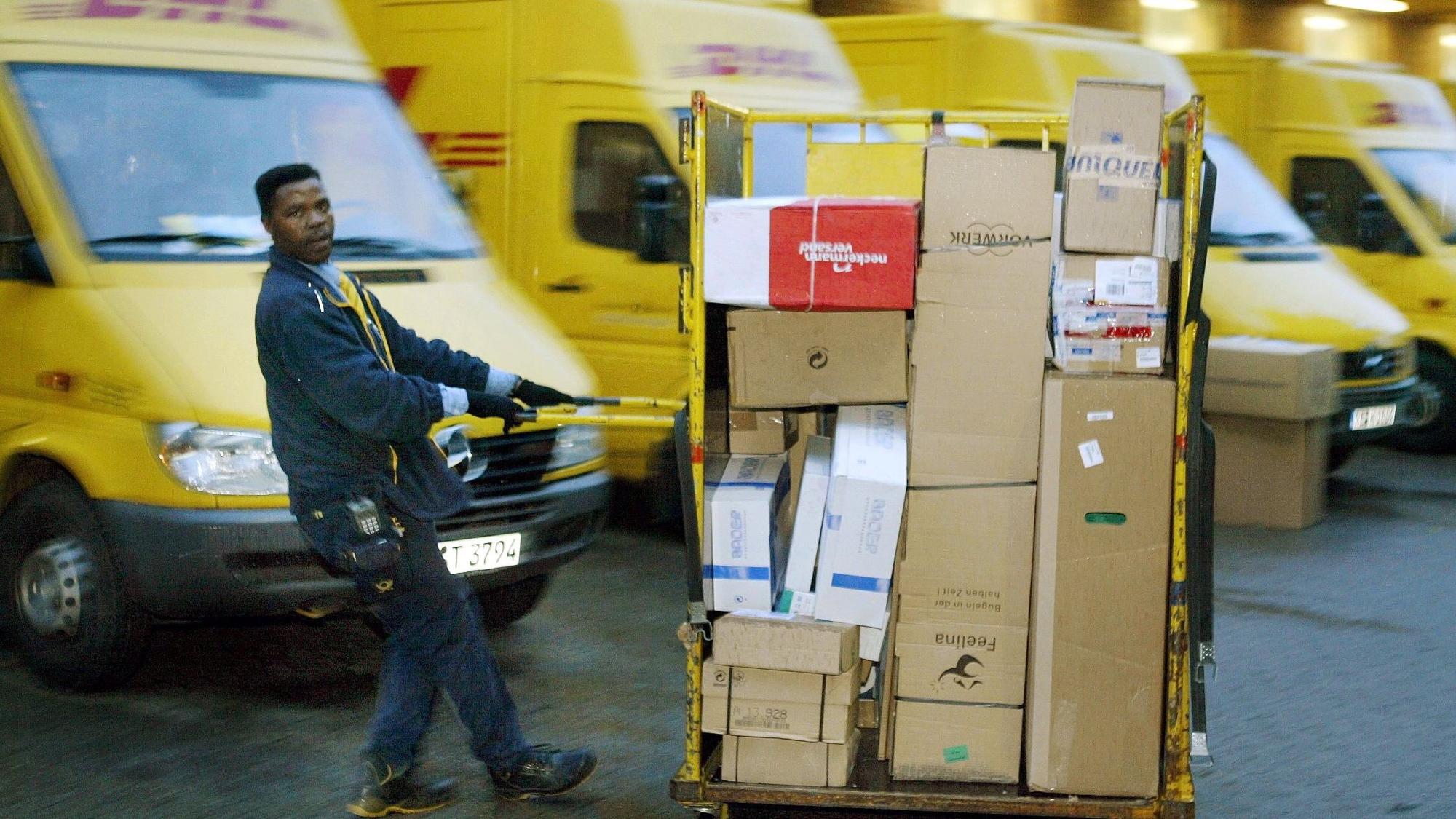 Ein Zusteller der DHL zieht in Dortmund einen Paketwagen zu seinem Fahrzeug (Archivfoto vom 21.10.2003).
