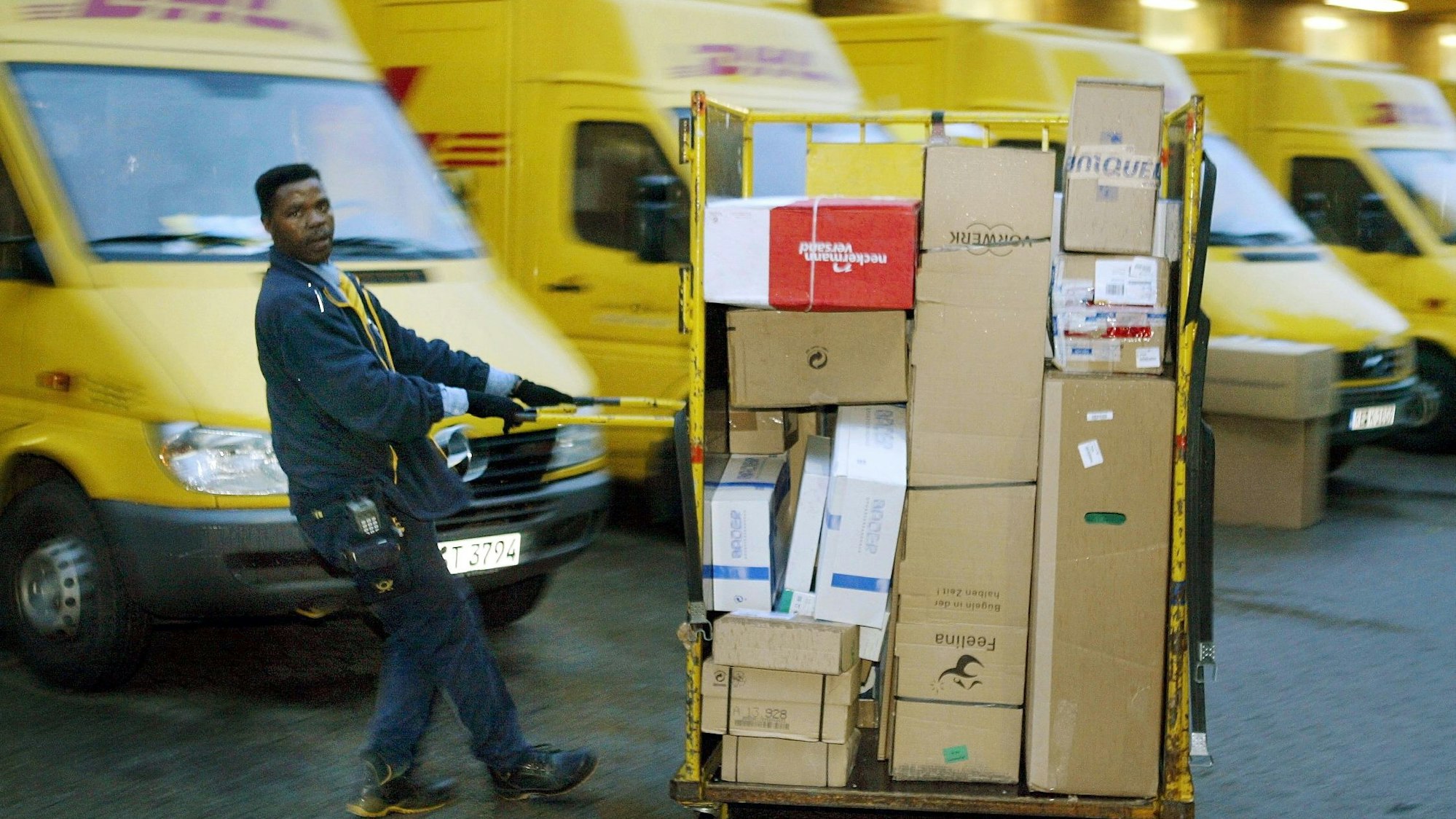 Ein Zusteller der DHL zieht in Dortmund einen Paketwagen zu seinem Fahrzeug (Archivfoto vom 21.10.2003).