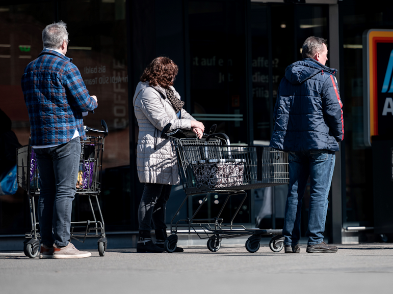 Menschen warten mit Abstand zueinander vor einer Filiale von Aldi Süd in Mülheim auf Einlass. Durch die Corona-Pandemie darf nur noch eine begrenzte Anzahl an Menschen gleichzeitig in den Markt.