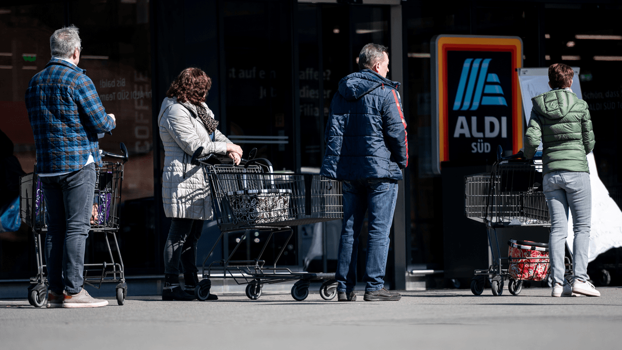 Menschen warten mit Abstand zueinander vor einer Filiale von Aldi Süd in Mülheim auf Einlass. Durch die Corona-Pandemie darf nur noch eine begrenzte Anzahl an Menschen gleichzeitig in den Markt.
