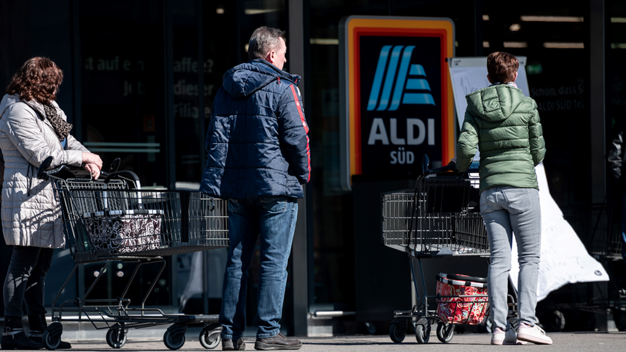 Menschen warten mit Abstand zueinander vor einer Filiale von Aldi Süd in Mülheim auf Einlass. Durch die Corona-Pandemie darf nur noch eine begrenzte Anzahl an Menschen gleichzeitig in den Markt.
