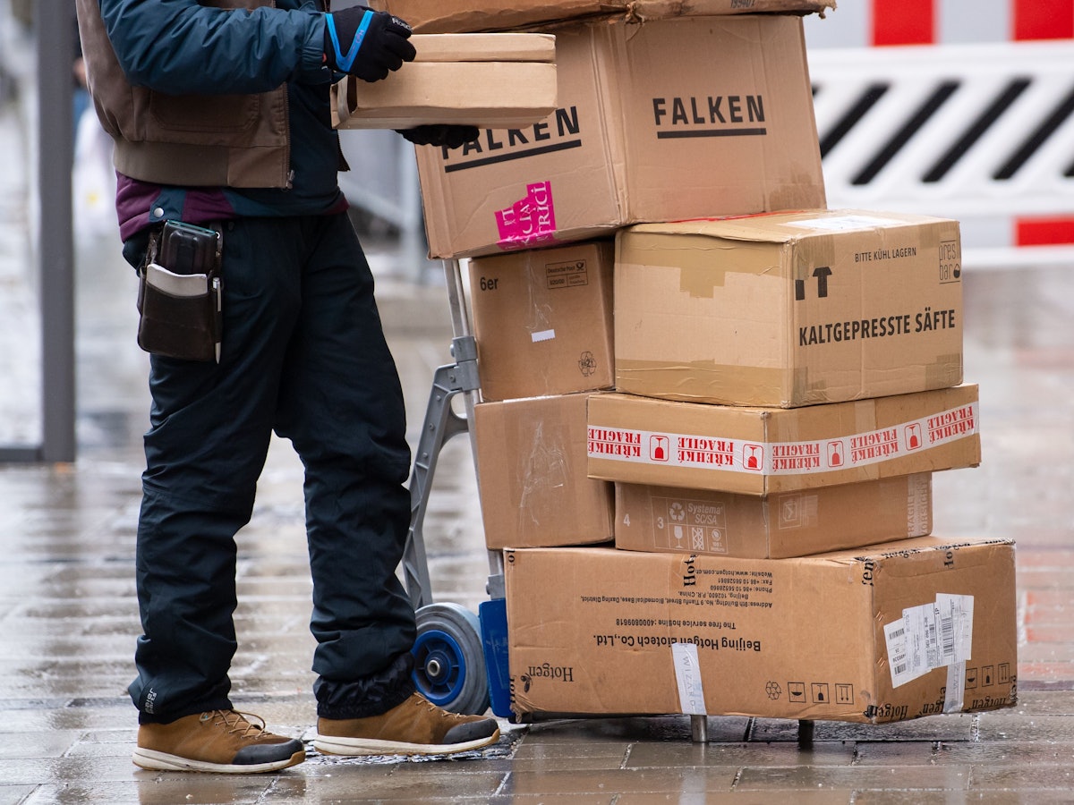 Ein Paketbote liefert in der Innenstadt seine Pakete aus.