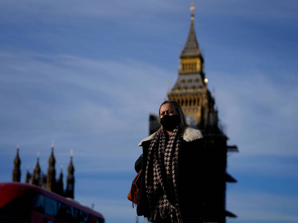 Eine Frau mit Mund-Nasen-Schutz überquert die Westminster Bridge.