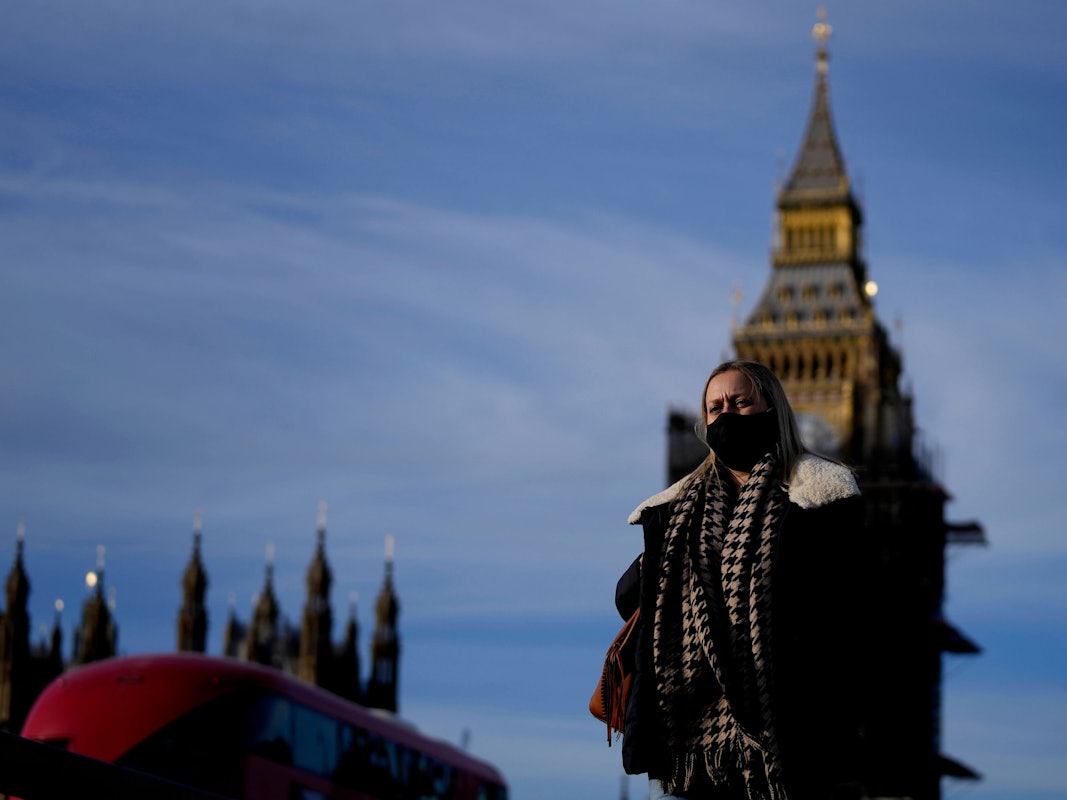 Eine Frau mit Mund-Nasen-Schutz überquert die Westminster Bridge.