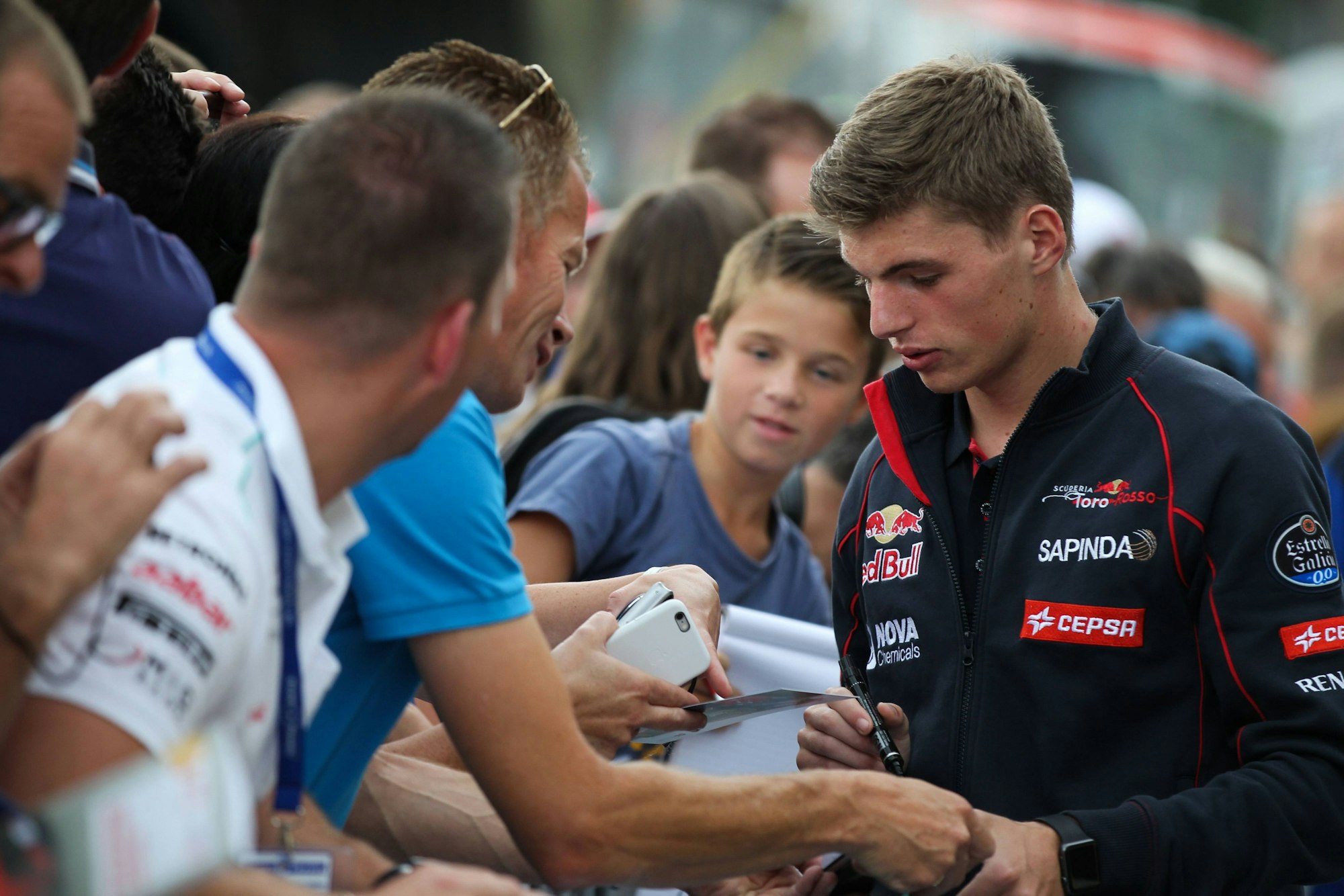 Der junge Max Verstappen schreibt Autogramme.