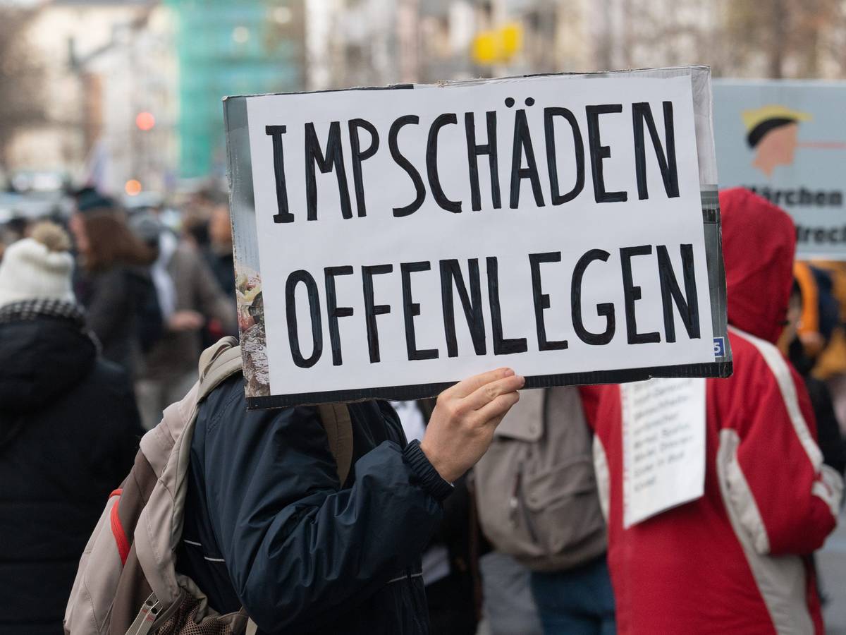 Ein Teilnehmer einer Demonstration hält ein Schild mit der Aufschrift „Impfschäden offenlegen“ in der Hand.